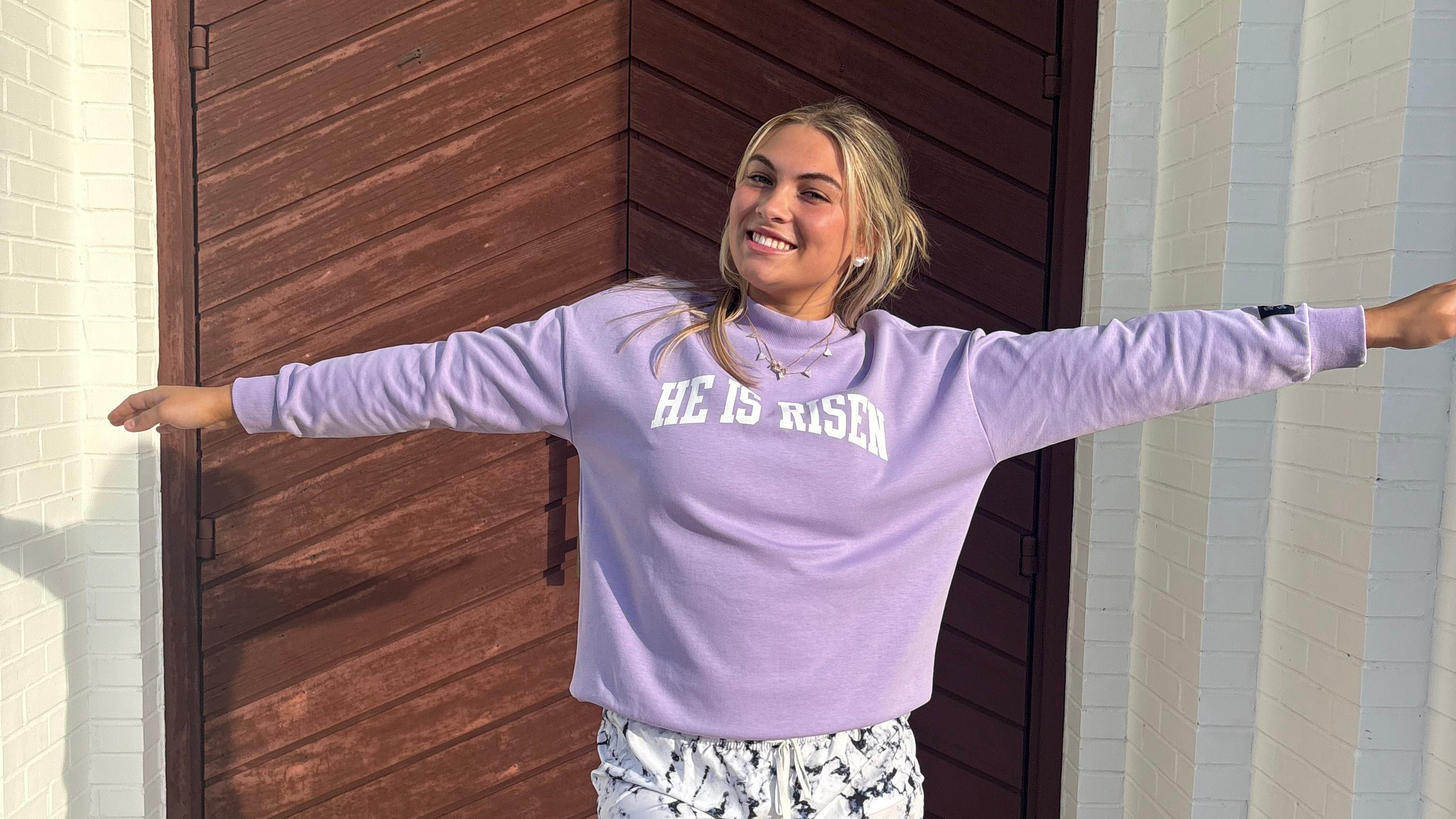 Person wearing a purple sweatshirt and patterned shorts standing on a set of stairs.