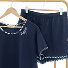 Navy blue outfit with white trim on a wooden rack against a white wall.