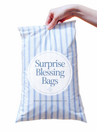 Hand holding a blue and white striped bag labeled 'Surprise Blessing Bags' on a white background.