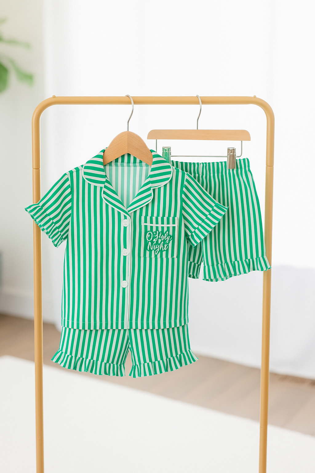 Green and white striped pajama set on a hanger against a white background