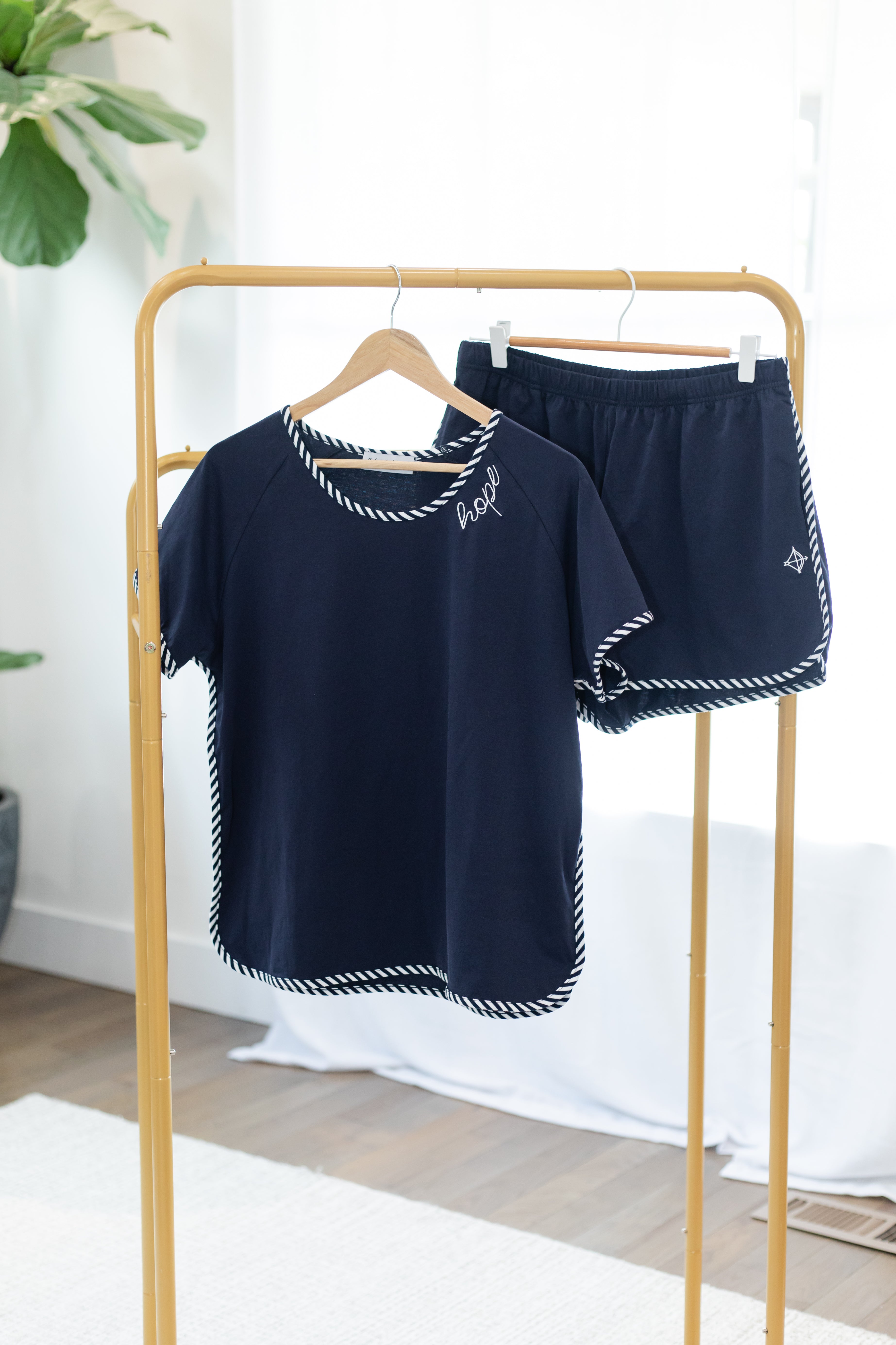 Navy blue pajama set with white trim on a wooden rack.